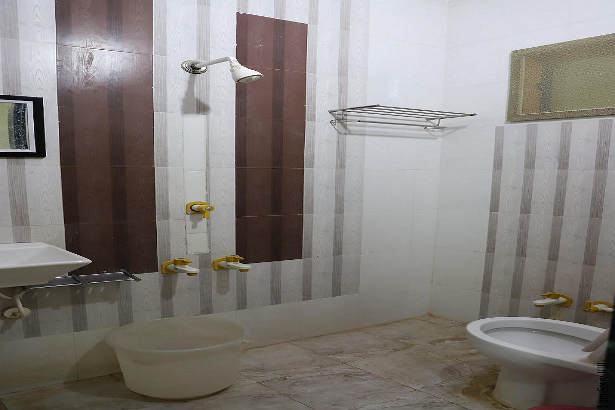 Spotless and modern washroom in Hotel Somnath Sagar's double bed room, featuring a clean toilet, shower, and vanity.