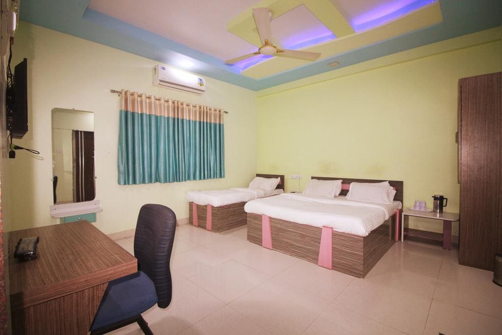 Amenities in Hotel Somnath Sagar's triple bed room in Veraval, including seating, storage, and a view of the surroundings.