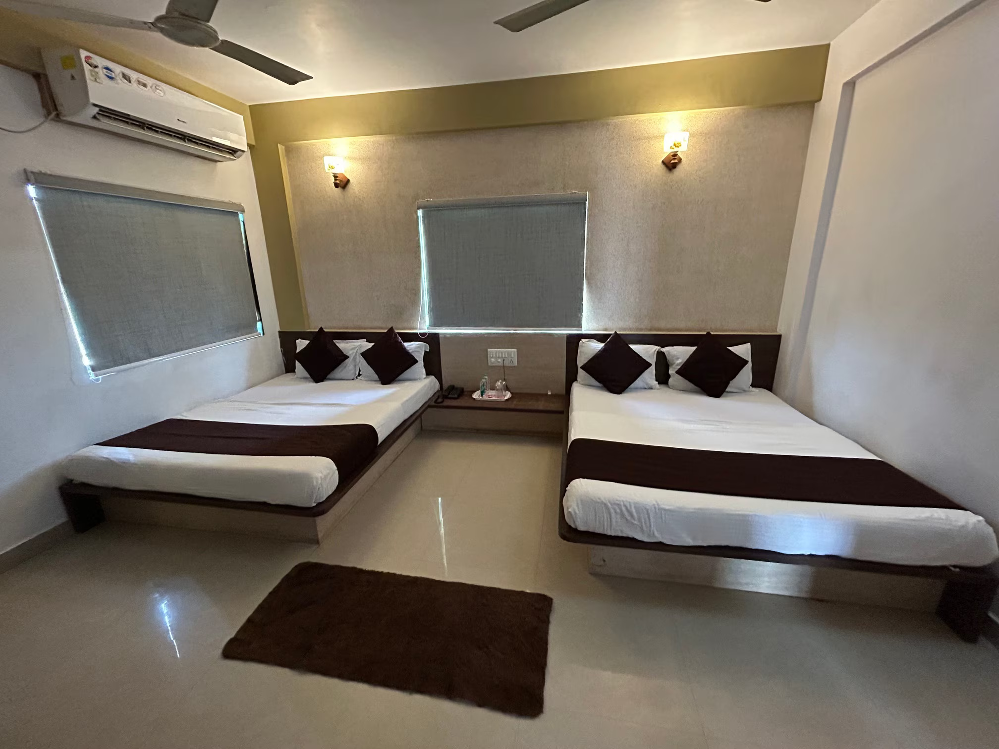 Deluxe Four Bed Room at Hotel Somnath Atithigruh, showcasing amenities like a TV and seating area.